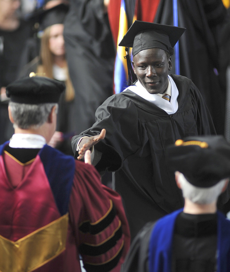 A Saint Joseph’s College graduate reaches for the hand of President Joe Lee during commencement excercises in Standish last week.