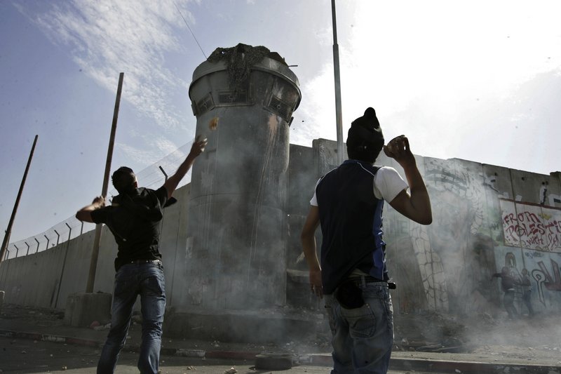 Masked Palestinian demonstrators hurl stones at an Israeli military watchtower during clashes Friday with Israeli troops at the Qalandiya checkpoint between the northern West Bank and Jerusalem. It is one of the rawest points of friction between Israel and the Palestinians.