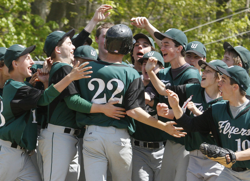 Mitch Newlin of Waynflete is welcomed by his teammates Saturday after hitting a two-run homer in the second inning of the second game against North Yarmouth Academy. NYA won 14-8 after Waynflete won the opener, 3-2. Newlin drove in six runs in the doubleheader.