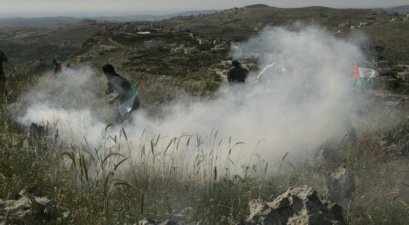Palestinians run from tear gas fired by Israeli soldiers during a demonstration against Jewish settlements in the northern West Bank village of Iraq Burin on Saturday. The settlement issue has been a stumbling block to resuming negotiations.