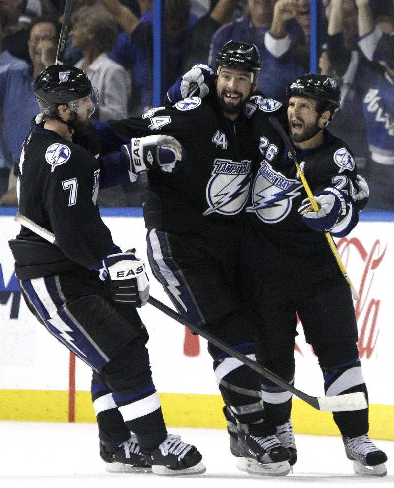 Martin St. Louis, right, celebrates with Brett Clark, left, and Nate Thompson after scoring an empty-net goal for Tampa Bay in the third period to seal a 5-3 victory over Boston in Game 4 of the Eastern Conference finals Saturday. The series heads back to Boston tied.