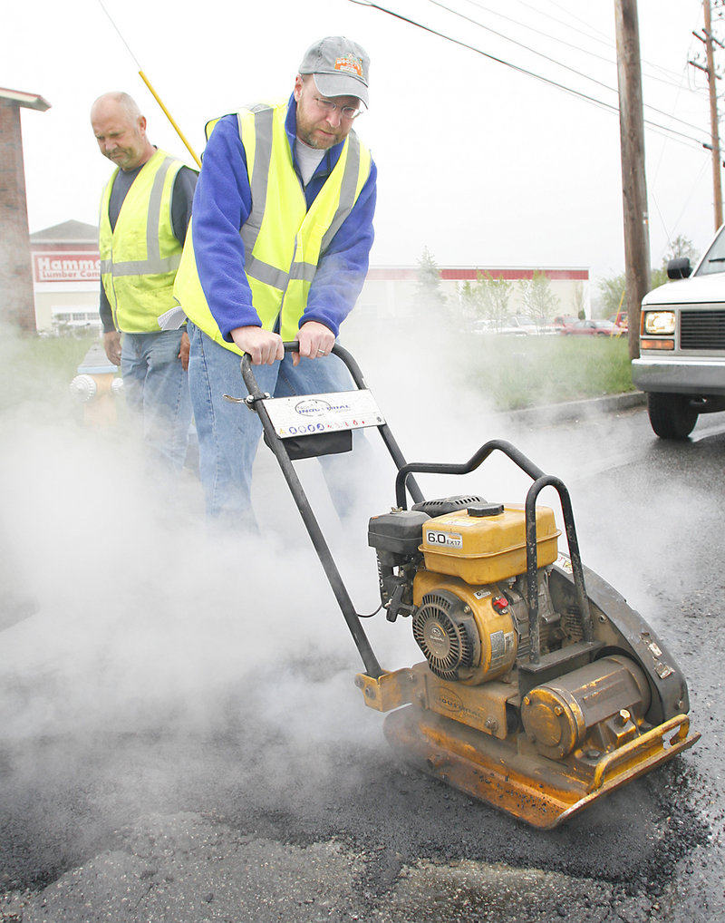 Reporter Ray Routhier uses a heavy compactor to flatten pavement patch as Kim Dolbow, a Portland Public Services Department maintenance worker, oversees his work.
