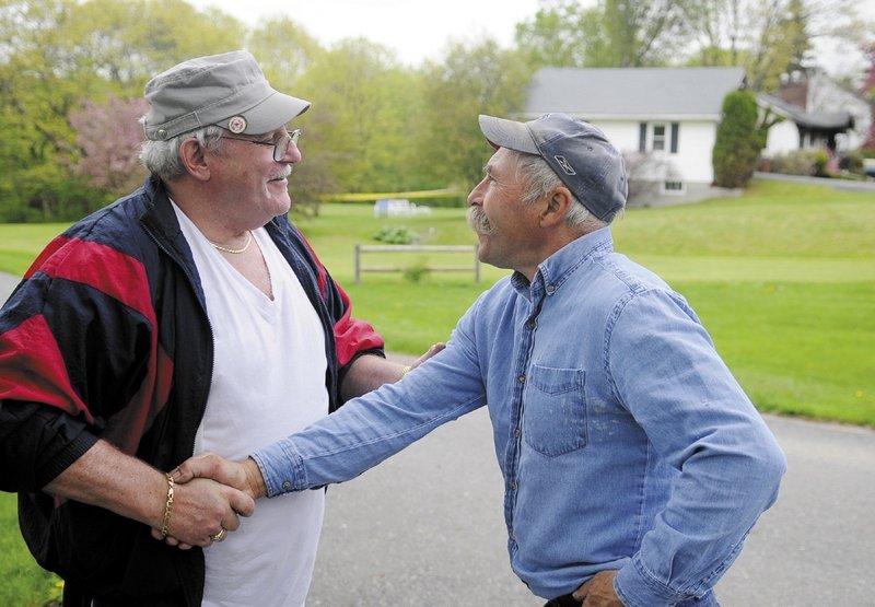 Augusta homeowner Ken Ward, left, is consoled by his friend Gary Paquette on Sunday morning. Ward’s home burned down early Sunday after being struck by a pickup truck.