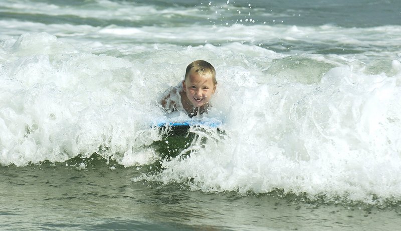 A boy beats the heat at Old Orchard Beach last summer by boogie boarding in the surf.