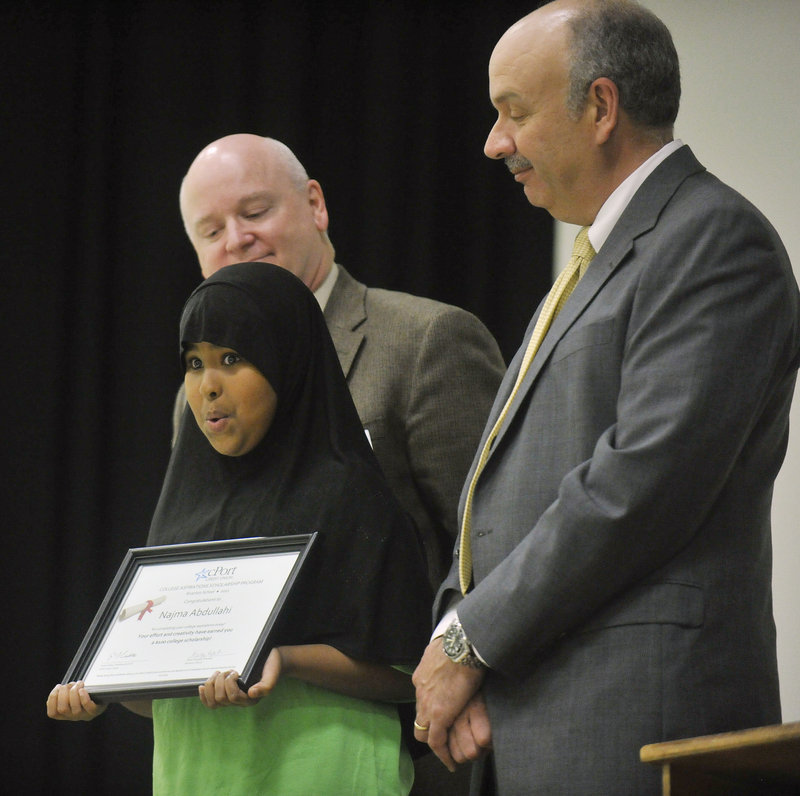 Najma Abdullahi, a fifth-grader at Riverton, holds her scholarship certificate on stage with schools Superintendent James Morse and cPort Credit Union president Gene Ardito.