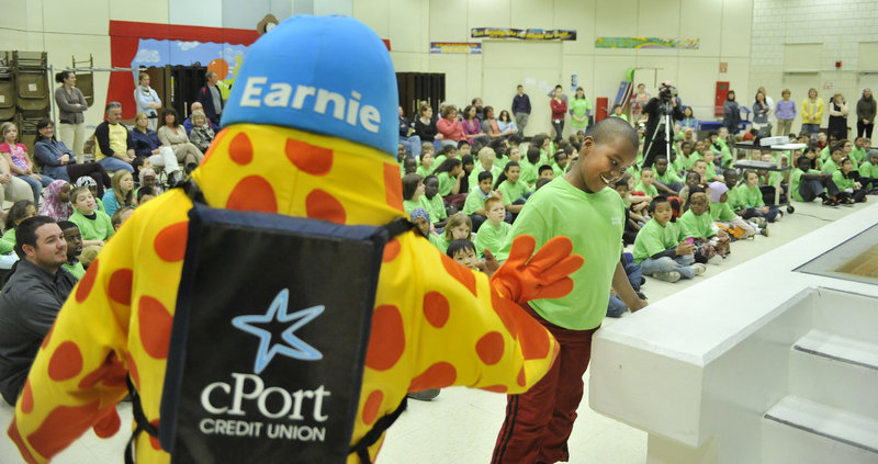 Fourth-grader Habiib Mohamed, who has ambitions to join the FBI, gets a high-five from Earnie, the cPort Credit Union mascot. CPort spent about $20,000 this year on the project, plus many hours of staff time to implement the event.