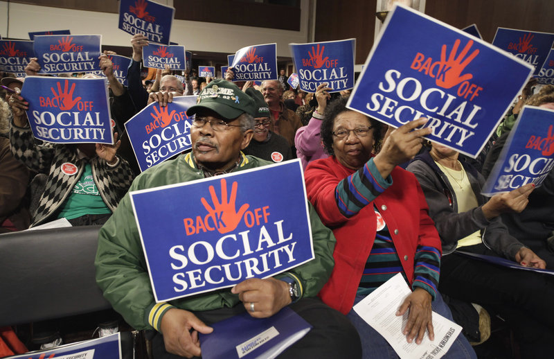 Audience members wave signs at a “Back Off Social Security” rally on Capitol Hill in Washington in March. A recent poll shows that most Americans don’t believe Medicare and Social Security will need to be trimmed in order to balance the federal budget.