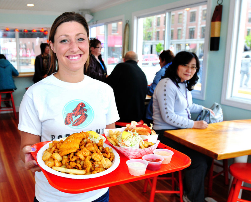 Server Kara Maxsimic serves a Fisherman’s Platter (haddock, scallops, clams, french fries and coleslaw) along with a lobster roll (drawn butter, no mayo) at Portland Lobster Co., which has reopened for the season.
