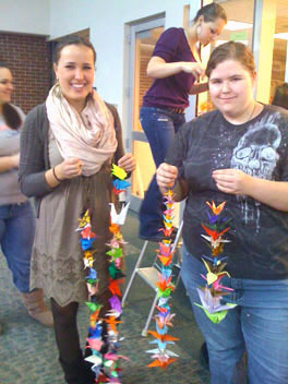 Bonny Eagle High School students Viktoria Karsten, left, and Julia Tracy help hang some of the 700 paper cranes created to raise funds to benefit Japanese disaster relief.
