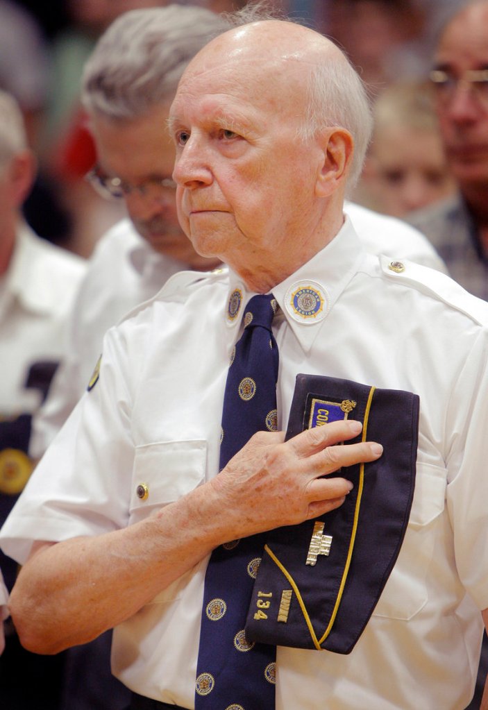 Gerald Burggren of Alfred, a Navy veteran from World War II, holds his cap over his heart during the playing of taps at Massabesic High School on Thursday.
