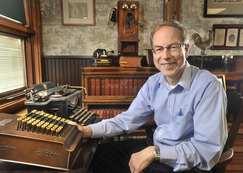 Peter Geiger sits with equipment, books, almanacs and other memorabilia at the company’s headquarters in Lewiston. One of his favorites is the “Guide to Kissing” almanac from the 1890s.