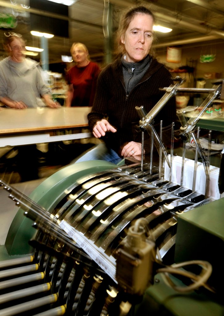 Sheila Vinal pulls newly printed compact planners from a collating machine at Geiger’s Lewiston plant. It makes and distributes promotional material.