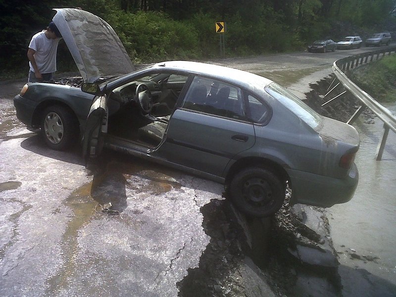 Adam Cooley of Barre, Vt., checks the damage to the engine of his 2001 Subaru Legacy in Barre Town, Vt. Flash floods triggered by thunderstorms roared through central Vermont on Friday.