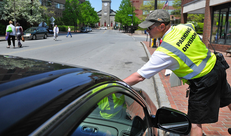 Parking Control Officer Chuck Fagone tickets a car for an expired meter on Temple Street last Friday. Fagone said he tickets an average of 75 vehicles a day. Ending the ticket forgiveness program has boosted the city’s bottom line.