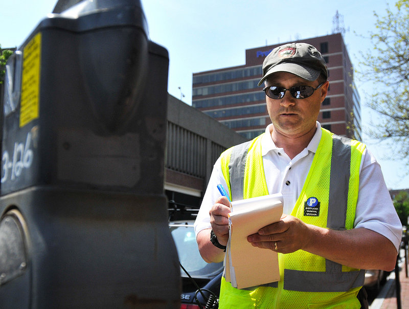 Parking Control Officer Chuck Fagone writes a ticket at a meter in Portland’s Old Port.