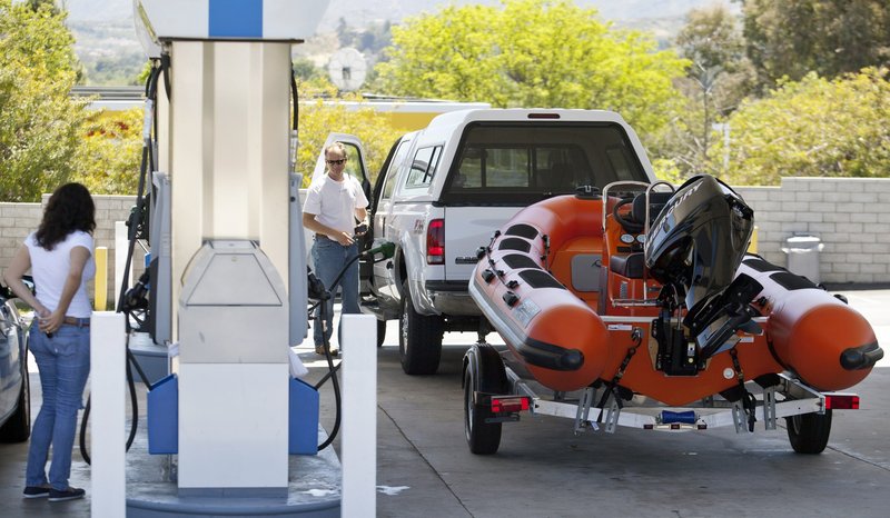 Travelers fill up their tanks at a gas station for an early start on the Memorial Day weekend traffic in Valencia, Calif., on Friday. Gas prices still topping the $4-a-gallon mark in much of the country are forcing motorists to spend more on fill-ups and doing more complicated math to make the summer budget work.