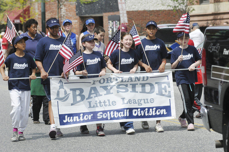 A local softball league is represented by some flag-waving players Monday. The parade included color guards from veterans organizations, bands from Portland and Deering high schools, a flotilla of pageant queens, and Scout groups.