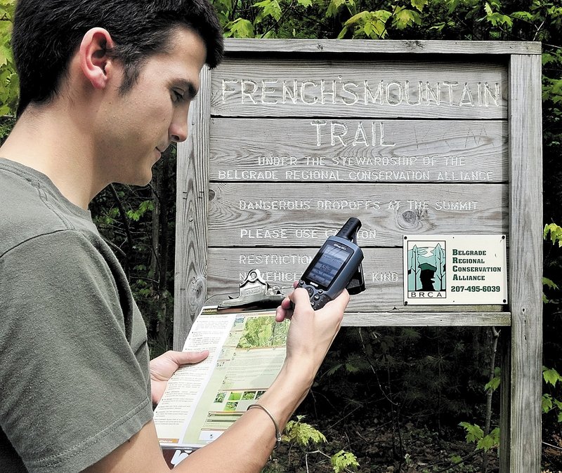 Joel Alex checks his GPS unit for a kiosk sign at the head of a trail leading to French’s Mountain in Rome.
