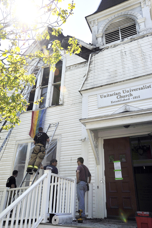 Brunswick firefighters cover damaged windows in the aftermath of an early morning fire at the Unitarian Universalist Church on Pleasant Street in Brunswick.