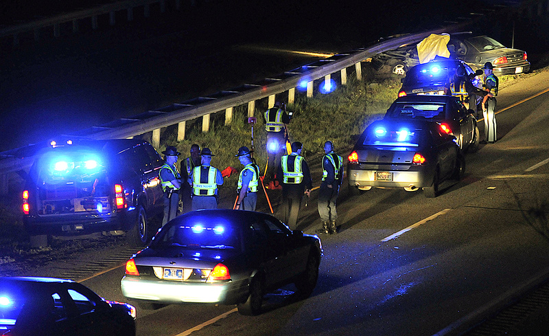 Maine State Police troopers converge at the scene of a crash just off Exit 63 on Interstate 95 late Monday night following a shooting and police chase. After the car visible at the top was stopped by spike mats, the driver, Nathaniel Gordon, killed himself, police say. He earlier had killed his wife, Sarah Gordon, in Winslow, according to police.