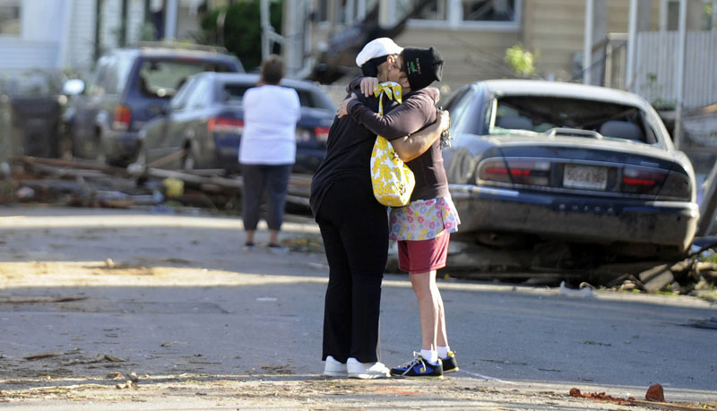 People embrace on a street damaged by Wednesday's tornado in Springfield, Mass., as residents of 19 small communities in central and western Massachusetts were left to deal with widespread damage today.