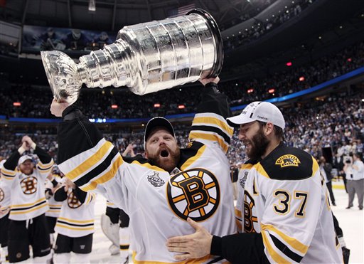 Boston Bruins goalie Tim Thomas hoists the cup with the help of teammate Patrice Bergeron following the Bruins' 4-0 win over the Vancouver Canucks in Game 7 of the NHL hockey Stanley Cup Finals on Wednesday, June 15, 2011, in Vancouver, British Columbia. (AP Photo/The Canadian Press, Jonathan Hayward) CANADA CANADIAN BRITISH COLUMBIA B.C. SPORTS PLAY ICE HOCKEY GAME ACTION COMPETITIVE COMPETITION COMPETE ATHLETICS ATHLETE NHL NATIONAL HOCKEY LEAGUE PLAYOFFS PLAYOFF WESTERN CONFERENCE SEMIFINAL STANLEY CUP