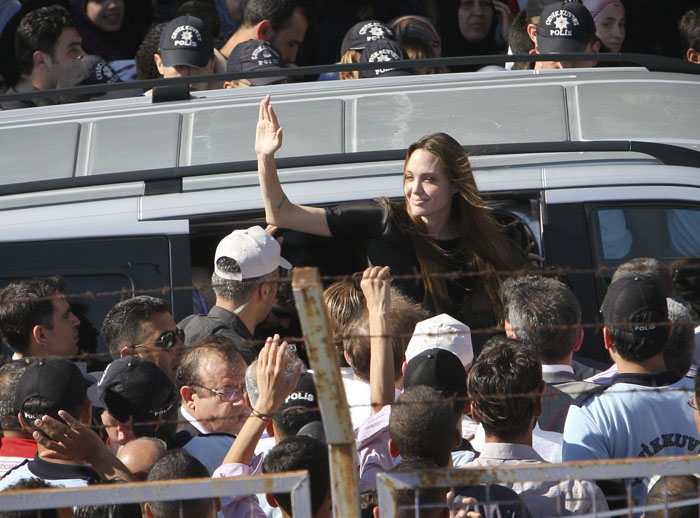 Angelina Jolie waves as she exits a van surrounded by Syrian refugees at the Altinozu refugee camp near the Syrian border today.