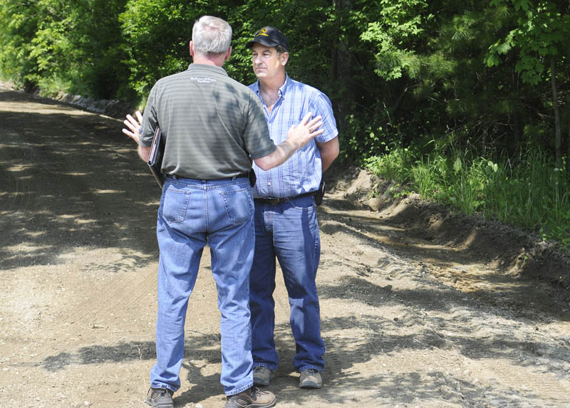 DIG IT: Dennis Hayden, left, of the Maine Public Utilities Commission damage prevention program advises Marshall Swan to stop grading the Tasker Road in Chelsea Wednesday morning. Swan was awarded a bid to grade eight dirt roads in the community. Hayden advised Swan that he violated state dig safe laws by grading without a permit.