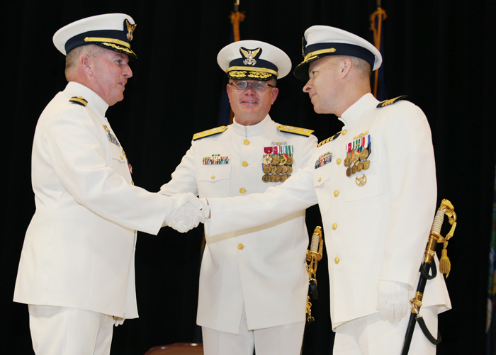 Capt. James McPherson, left, shakes hands with Capt. Christopher Roberge, right, who replaces him as Sector Northern New England commander during a change of command ceremony today in Cape Elizabeth. Rear Adm. Daniel Neptun is at center.