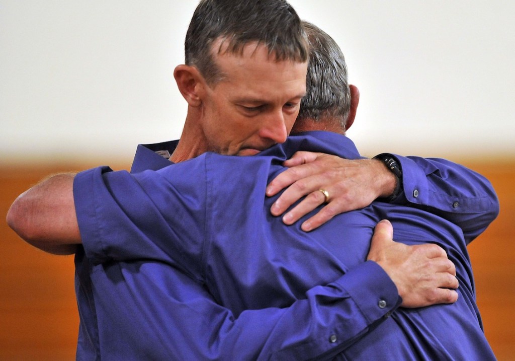 Jeff Bagley hugs his father Ralph Bagley before the funeral for Amy, Coty and Monica Lake at Dexter Regional High School in Dexter on Saturday.