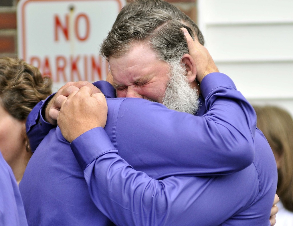 Andrew Higgins, facing, and Jeff Bagley, embrace after the funeral for Amy, Coty and Monica Lake at Dexter Regional High School in Dexter on Saturday. Jeff Bagley is the brother of Amy Lake and Higgins was close friend and pallbearer for the service.