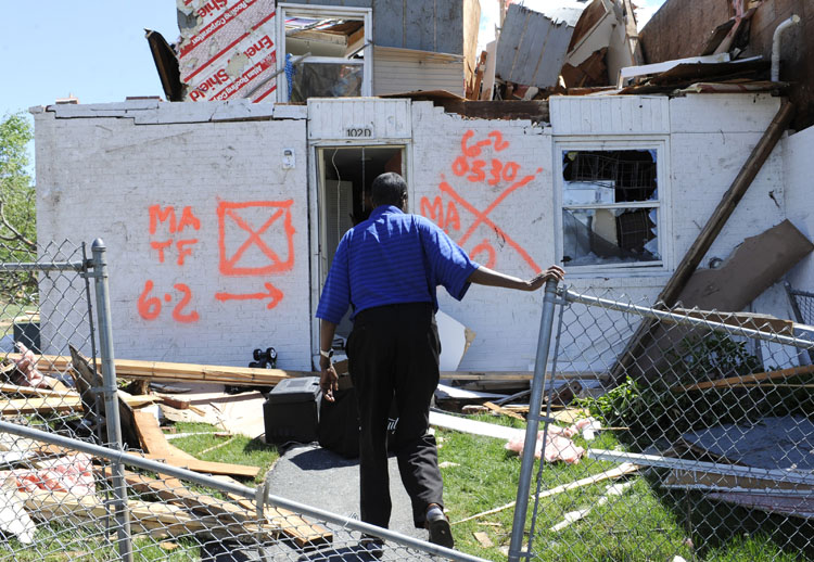 A man enters his home today, a day after a tornado struck iSpringfield, Mass. Two late-afternoon tornadoes shocked emergency officials Wednesday with their suddenness and violence and caused the state's first tornado-related deaths in 16 years.