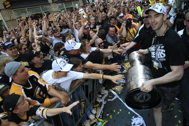 Bruins captain Zdeno Chara carries the Stanley Cup as fans reach to touch the trophy during a rally in celebration today in Boston.