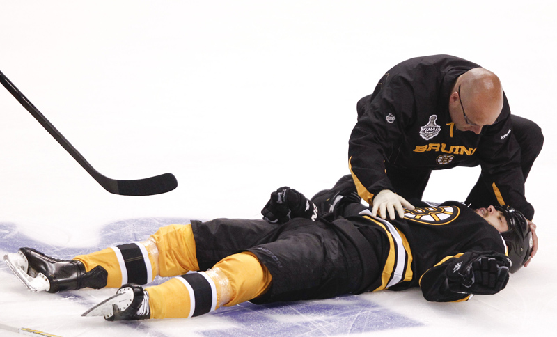 Boston Bruins right wing Nathan Horton (18) is tended to by a trainer after a blind side hit by Vancouver Canucks' Aaron Rome in the first period during Game 3 of the NHL hockey Stanley Cup Finals on Monday.