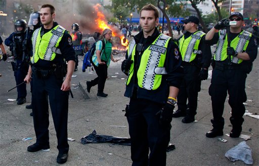 Police officers stand together after rioters burned police cars following the Vancouver Canucks being defeated by the Boston Bruins in the NHL Stanley Cup Final in Vancouver, British Columbia, Wednesday, June 15, 2011. Angry, drunken revelers ran wild Wednesday night after the Vancouver Canucks' 4-0 loss to Boston in Game 7 of the Stanley Cup finals, setting cars and garbage cans ablaze, smashing windows, showering giant TV screens with beer bottles and dancing atop overturned vehicles. (AP Photo/The Canadian Press, Darryl Dyck) CANADA CANADIAN BRITISH COLUMBIA B.C. VANCOUVER