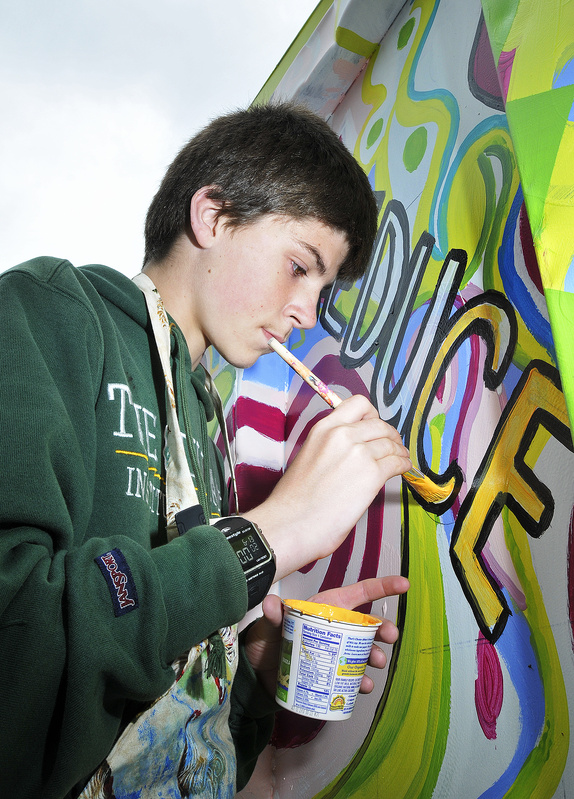 Tim Corsello paints letters on the container to encourage recycling.