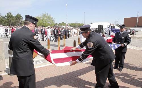 Ian Canavan, Jim Backman and Bill Price, firefighters at Brunswick Naval Air Station, fold the flag at the base for the last time on Tuesday.