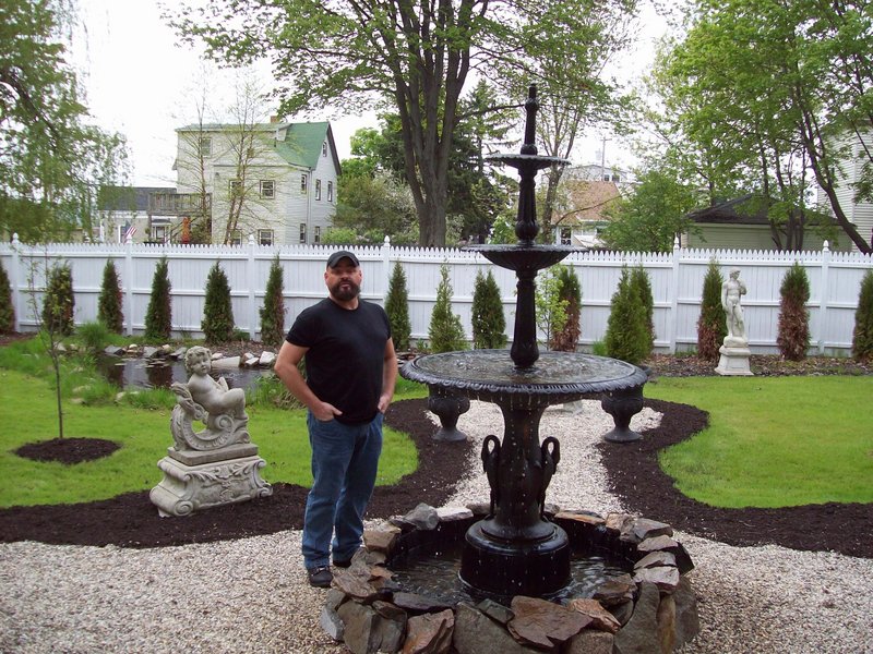Miguel Collins next to the yard’s centerpiece fountain.