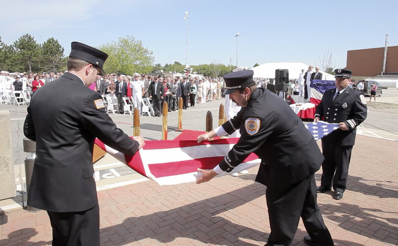 From left, Ian Canavan, Jim Backman and Bill Price, firefighters with the Brunswick Naval Air Station, take down the American flag for the last time during a disestablishment ceremony at the base Tuesday.