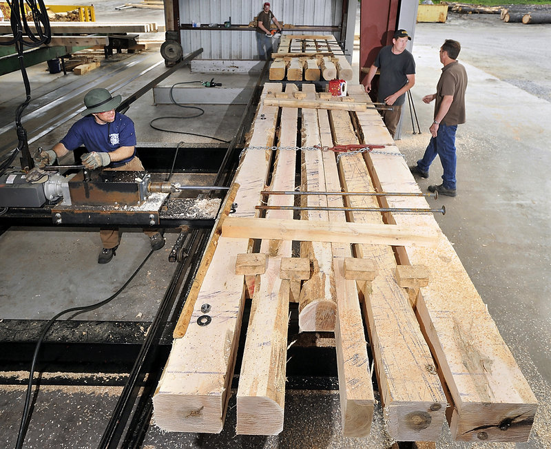 Thomas Thayer, left, drills holes in hardwood timbers for bolts that will hold the mat together. Others working the project are Denis Couture and Shawn Brown. Owner Fred Decker is at right.