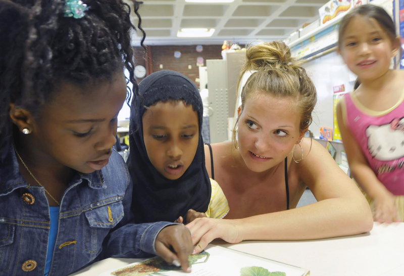 Falmouth High School's Ellie MacEwan reads with Reiche Elementary School first-graders Sefora Kabala, left, and Mane Nour. "I love interacting with the kids and I love listening to what they have to say about the world," MacEwan said.