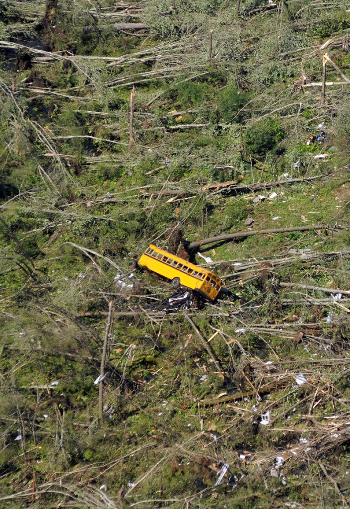 In the aftermath of Wednesday’s violent tornados, this aerial photo in Brimfield, Mass., shows a school bus overturned by high winds, surrounded by knocked-down trees at the Village Green Family Campground. At least three people died – the state’s first tornado-related deaths in 16 years.