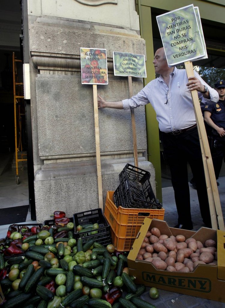 A farmer places a placard reading “Because of such big lies, nobody is buying my vegetables” as protesting farmers dump some 700 pounds of cabbage, tomatoes, peppers, cucumbers and other produce outside the German consulate in Valencia, Spain, on Thursday.
