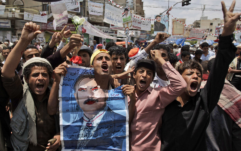 Anti-government protesters hold a defaced poster of Yemeni President Ali Abdullah Saleh as they demand his resignation in San'a, Yemen, on Saturday.