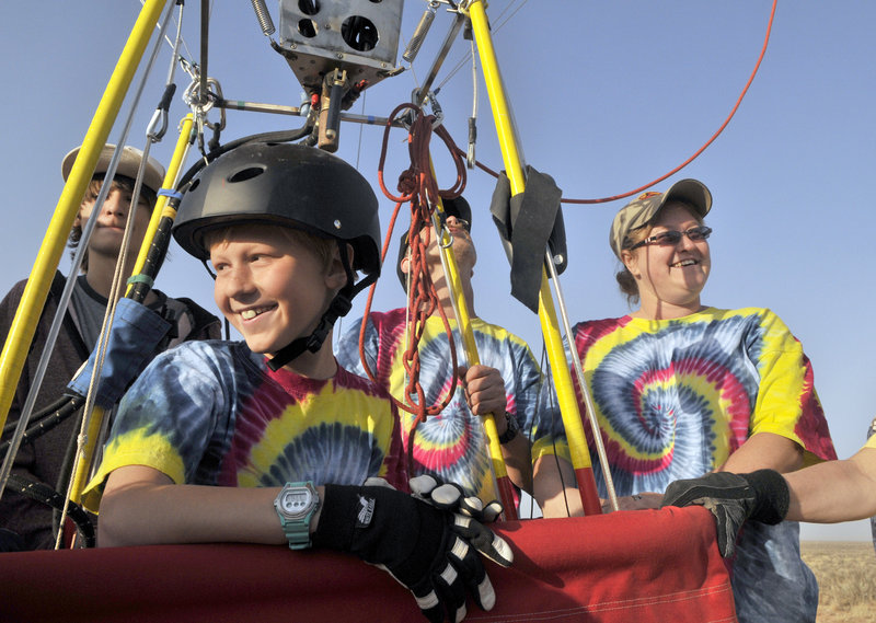 Bobby Bradley, 9, of Albuquerque, N.M., smiles after landing his hot air balloon after a solo flight near Tome, N.M., on Saturday. Behind him in tie-dyed shirts are his father, Troy Bradley, and mother, Tami Bradley.
