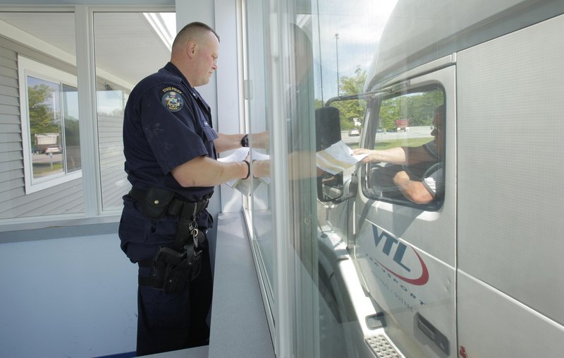 Maine State Police Trooper Shane Northup takes paperwork from a truck driver during a truck check at a weigh station off the northbound lane of the Maine Turnpike in York on Tuesday.
