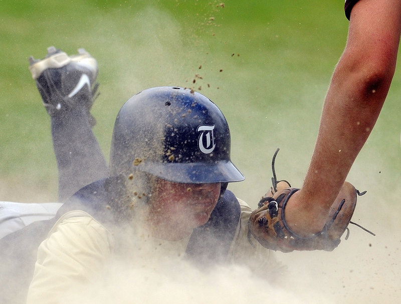 Brandon Metevier of Traip Academy stirs up dust with a headfirst slide and beats a tag by Monmouth Academy third baseman Josh Fournier during Monmouth's 12-5 victory Tuesday.