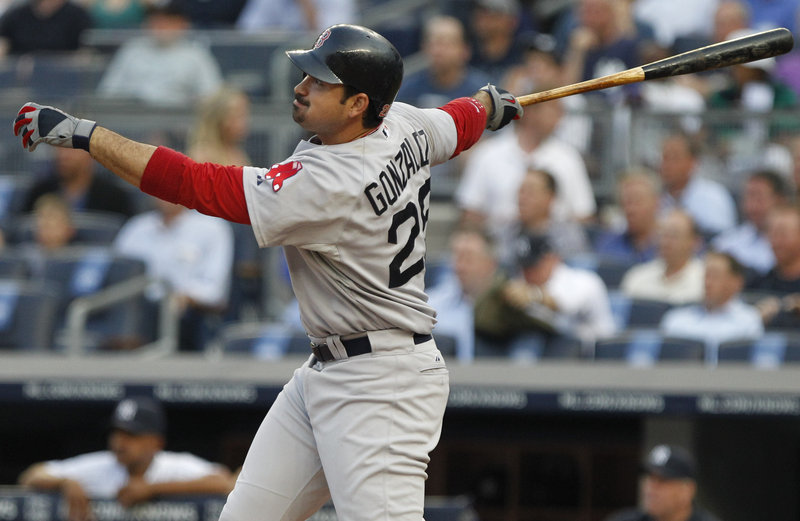 Boston’s Adrian Gonzalez watches the flight of his RBI triple in the first inning Tuesday night at Yankees Stadium in New York. The Red Sox survived early wildness by starter Jon Lester to open their three-game series with a win.