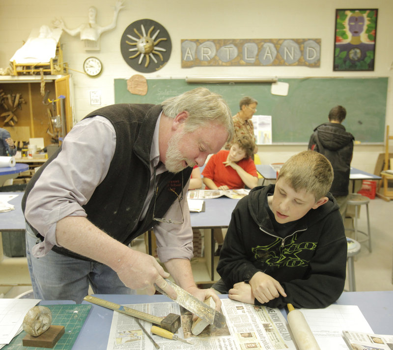 Thomas Block teaches freshman Derek Flowers how to use a rasp file to sculpt soapstone at Wiscasset High School.