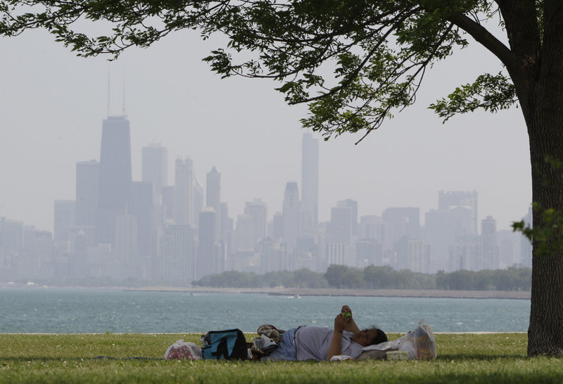 A woman cools off in the shade of a tree Wednesday at Montrose Beach in Chicago, where the temperature peaked at 94 degrees. The city’s record for the date is 97, set in 1933.